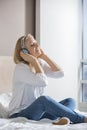 Relaxed mid adult woman enjoying music on headphones in bedroom Royalty Free Stock Photo