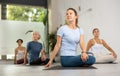 Calm European middle-aged woman practicing Half Lord of the fishes pose or Ardha Matsyendrasana during group yoga Royalty Free Stock Photo