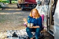 Relaxed Middle aged woman eating veggie salad outside camper van in the forest camp during road trip lunch. Enjoying nomad