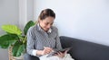 Relaxed woman sitting on couch and using digital tablet.