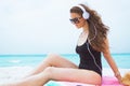 Middle age woman listening to music while sitting on round towel Royalty Free Stock Photo