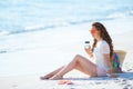 Relaxed woman on ocean coast drinking coffee while sitting