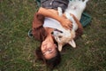 Relaxed moment captured as a woman lies on the grass with to a Corgi dog