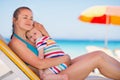 Relaxed mother on sun bed embracing baby