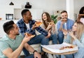 Relaxed multiracial friends having home party, eating pizza in living room, chatting, laughing, spending time together Royalty Free Stock Photo