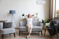 Relaxed older woman sitting on couch in air conditioner room