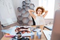 Relaxed pensive curly young woman photographer sitting on workplace Royalty Free Stock Photo