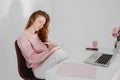 Relaxed pensive young woman sitting at workplace in office and making notes. Royalty Free Stock Photo