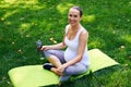 Relaxed pregnant sportive woman with bottle of water sitting in