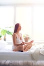 Relaxed pregnant woman doing meditation in bedroom