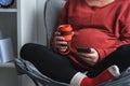 Relaxed pregnant woman using smart phone