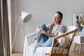 Relaxed redhead girl is sitting on modern chair in light cozy room at home Royalty Free Stock Photo