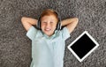 Relaxed preteen boy listening to music on pad, using headset Royalty Free Stock Photo