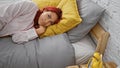 Relaxed redhead woman in home comfort, looking at alarm clock, resting in her cozy bed, concentrating on morning time in bedroom Royalty Free Stock Photo