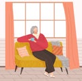 Relaxed senior grey haired woman in glasses sitting on couch drinking tea thinking about something