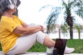 Relaxed senior woman with headphones sitting outdoors  looking at sea. Laptop computer on bench Royalty Free Stock Photo