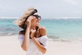 Relaxed short-haired woman posing on sea background. Outdoor shot of blithesome young lady in sunglasses enjoying