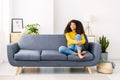 Relaxed smiling afro american woman sitting on sofa at home Royalty Free Stock Photo