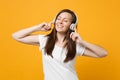 Relaxed smiling young woman in white casual clothes keeping eyes closed, listen music with headphones isolated on yellow Royalty Free Stock Photo