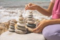 Relaxed spiritually woman hand arrangement pebble tower cobblestone sea coastline landscape closeup