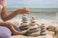 Relaxed spiritually woman hand arrangement pebble tower cobblestone sea coastline landscape closeup