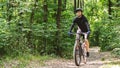 Relaxed sportsman enjoying cycling down forest trail