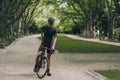 Relaxed sportsman standing with black bike at park