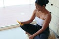 Relaxed sporty african woman checking social media using smartphone after exercise, in living room of home sitting on a mat