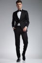 Relaxed stylish man wearing a black tuxedo walking