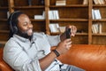 Relaxed African man listening music lying on the couch Royalty Free Stock Photo