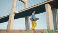 Relaxed teenager walking skateboard under city bridge. African skater relaxing Royalty Free Stock Photo