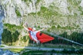 Relaxed tourist male in a hammock high up in a mountain, above the valley, secured with a via ferrata set on two steel wires