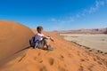 Relaxed tourist sitting on sand dunes and looking at the stunning view in Sossusvlei, Namib desert, best travel destination in Nam Royalty Free Stock Photo