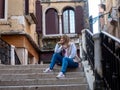 Relaxed tourist woman sitting on the stairs on a bridge in the city of Venice, Italy