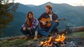 Relaxed tourists enjoy bonfire spend evening in mountains. Couple camp outdoors. Royalty Free Stock Photo