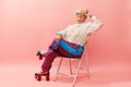 Relaxed vibe. Beautiful old woman, grandmother in stylish sportive trousers posing on vintage rollers over pink studio Royalty Free Stock Photo