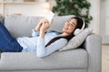 Relaxed Weekend. Happy Korean Girl In Wireless Headphones Listening Music On Smartphone Royalty Free Stock Photo