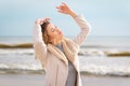 Relaxed woman, arms rised, enjoying spring sun, on a beautiful beach. Young lady feeling free, relaxed and happy Royalty Free Stock Photo