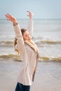 Relaxed woman, arms rised, enjoying spring sun, on a beautiful beach. Young lady feeling free, relaxed and happy Royalty Free Stock Photo