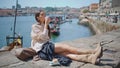 Relaxed woman drinking coffee sunny river embankment. Lady enjoying work break Royalty Free Stock Photo