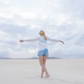 Carefree woman enjoying freedom on white sand dune at dusk. Royalty Free Stock Photo