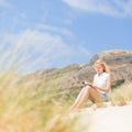 Woman reading book, enjoying sun on beach. Royalty Free Stock Photo