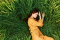 a relaxed woman enjoys summer lying in the tall green grass with her eyes closed. Photo taken from above