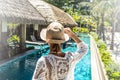 Relaxed woman in front of tropical house and swimming pool. Female traveler at luxury beach resort. Vacations and summer concept Royalty Free Stock Photo