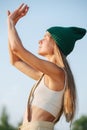 Relaxed woman in a green watch cap enjoying morning sun. Eyes closed.