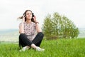 Relaxed woman listening music on headphones sitting down on lawn Royalty Free Stock Photo