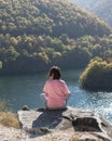 Relaxed woman listening music using wireless headphones among nature, enjoying scenic view, Rhodope mountains, Bulgaria
