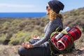 Relaxed woman in meditation position sitting on the rocks during travel backpack adventure leisure activity outdoor. Adult female