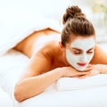 Relaxed woman with revitalising mask on face laying on mas