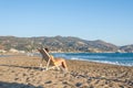 Relaxed woman sitting on a sunbed wearing headphones meditating listening to music on the beach at sunset or sunrise. Royalty Free Stock Photo